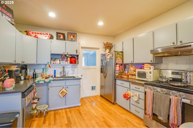 kitchen with stainless steel appliances, sink, backsplash, and light wood-type flooring