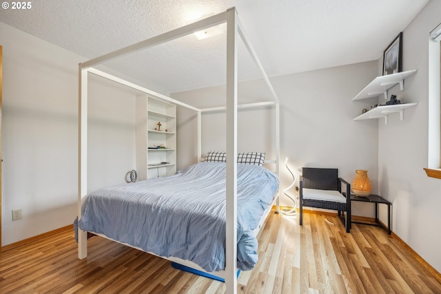 bedroom with a textured ceiling and wood finished floors
