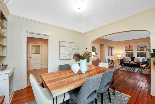 dining area featuring ornamental molding, dark wood-type flooring, and a textured ceiling