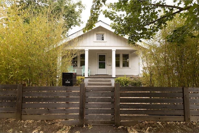 bungalow featuring board and batten siding, covered porch, a fenced front yard, and a gate