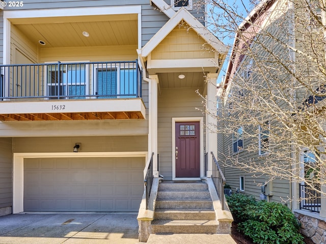 view of exterior entry featuring a garage, driveway, and a balcony