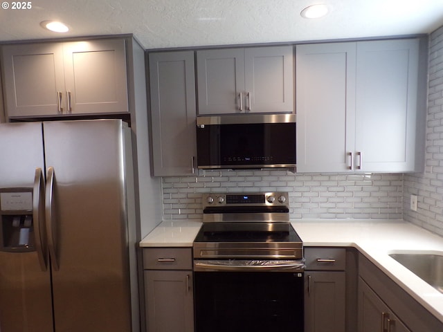 870 W Lincoln St, Woodburn, OR 97071 - kitchen with light countertops, decorative backsplash, gray cabinetry, and stainless steel appliances