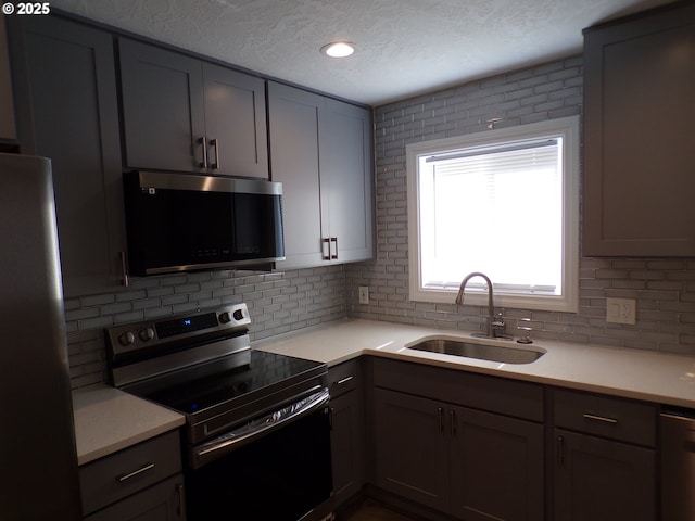 870 W Lincoln St, Woodburn, OR 97071 - kitchen featuring a sink, decorative backsplash, stainless steel appliances, and a textured ceiling