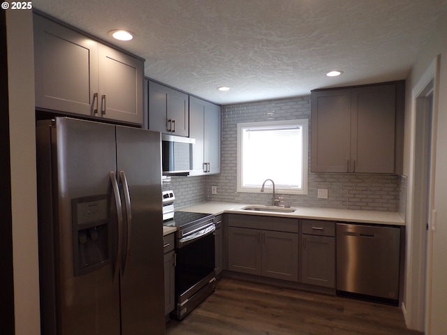 870 W Lincoln St, Woodburn, OR 97071 - kitchen featuring decorative backsplash, appliances with stainless steel finishes, a sink, light countertops, and dark wood-style floors