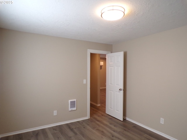 870 W Lincoln St, Woodburn, OR 97071 - empty room featuring a textured ceiling, baseboards, dark wood finished floors, and visible vents