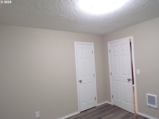 870 W Lincoln St, Woodburn, OR 97071 - unfurnished room featuring baseboards, dark wood finished floors, a textured ceiling, and visible vents