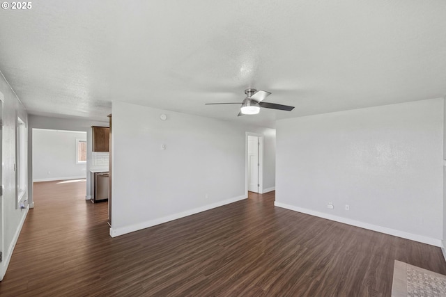 unfurnished living room featuring baseboards, ceiling fan, and dark wood-style floors