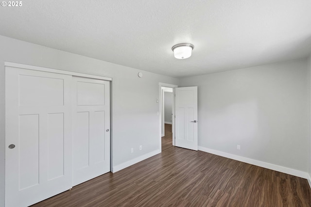 unfurnished bedroom with baseboards, a closet, and dark wood finished floors