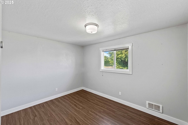 empty room with dark wood-style flooring, baseboards, visible vents, and a textured ceiling