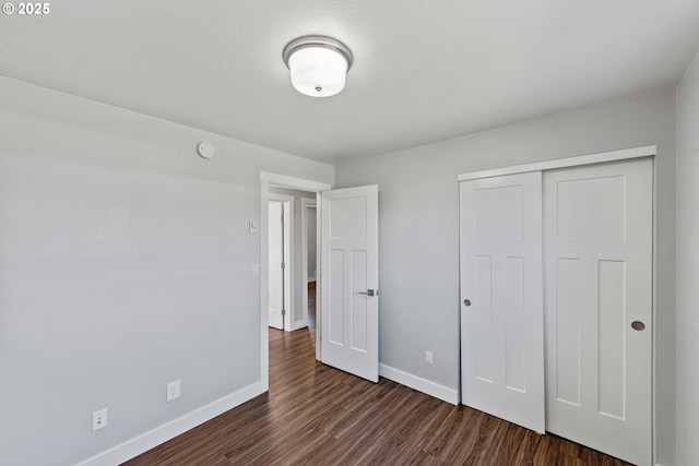 unfurnished bedroom featuring baseboards, a closet, and dark wood finished floors