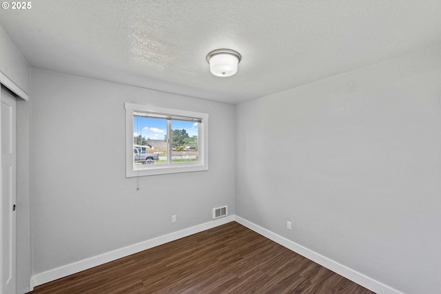 unfurnished bedroom with visible vents, a closet, baseboards, a textured ceiling, and dark wood finished floors