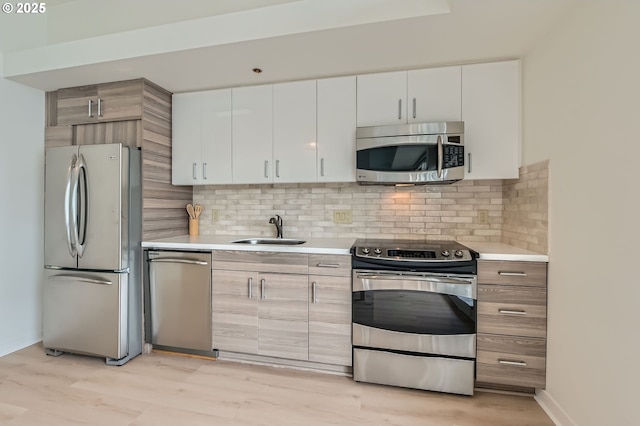 kitchen with stainless steel appliances, light countertops, a sink, and tasteful backsplash