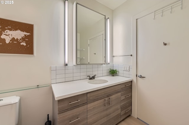 bathroom with decorative backsplash, vanity, and toilet