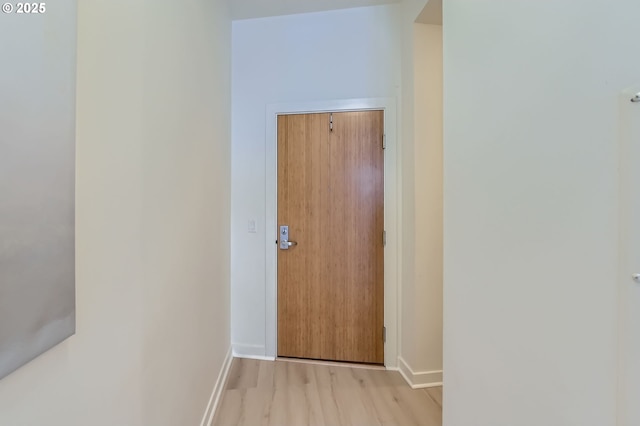 hall with baseboards and light wood-type flooring