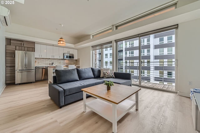 living area featuring a wall unit AC and light wood-type flooring