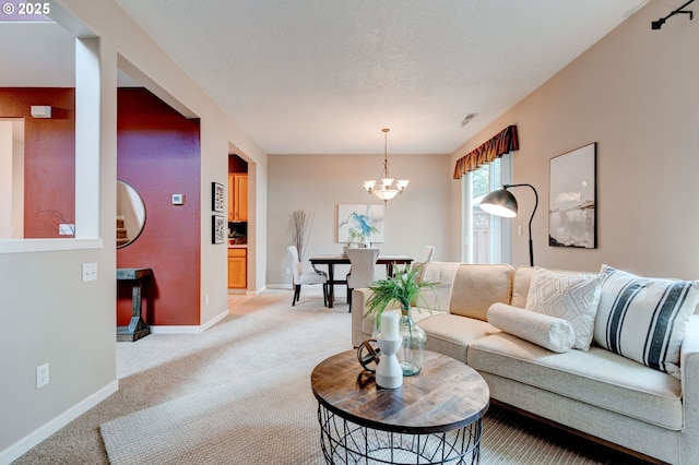 living room featuring light carpet, a textured ceiling, baseboards, and a notable chandelier