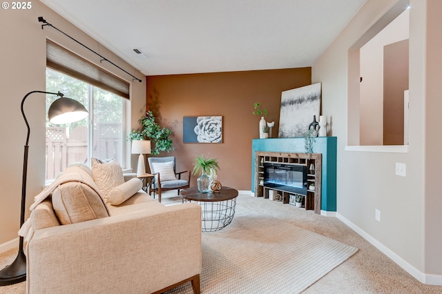 carpeted living room featuring a glass covered fireplace and baseboards