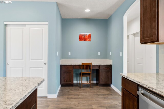 kitchen featuring light wood-style floors, stainless steel dishwasher, and dark brown cabinetry