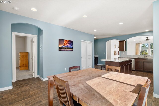 dining room with dark wood finished floors, recessed lighting, arched walkways, and baseboards