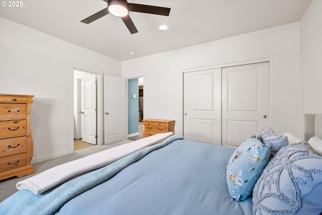 bedroom featuring a closet, baseboards, light colored carpet, and a ceiling fan