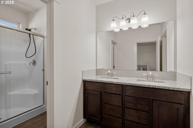 bathroom featuring a sink, double vanity, wood finished floors, and a shower stall