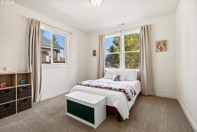 carpeted bedroom featuring visible vents, multiple windows, and baseboards