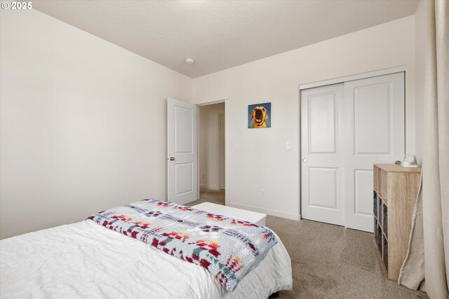 carpeted bedroom featuring a closet and baseboards