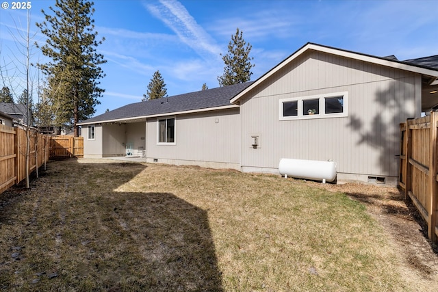 rear view of property with a shingled roof, a fenced backyard, a lawn, and crawl space