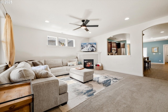 living room featuring a glass covered fireplace, recessed lighting, carpet flooring, baseboards, and ceiling fan