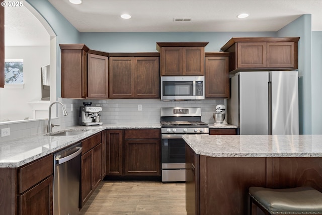 kitchen featuring tasteful backsplash, visible vents, light wood-style flooring, stainless steel appliances, and a sink