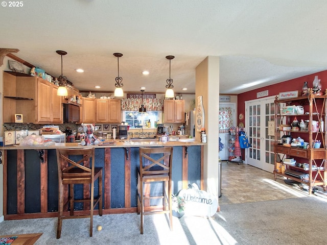 kitchen with french doors, a breakfast bar, kitchen peninsula, and pendant lighting