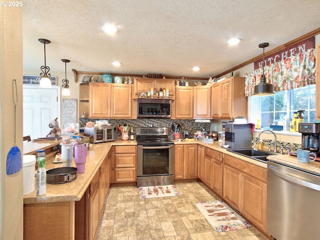 kitchen featuring pendant lighting, stainless steel appliances, sink, and backsplash