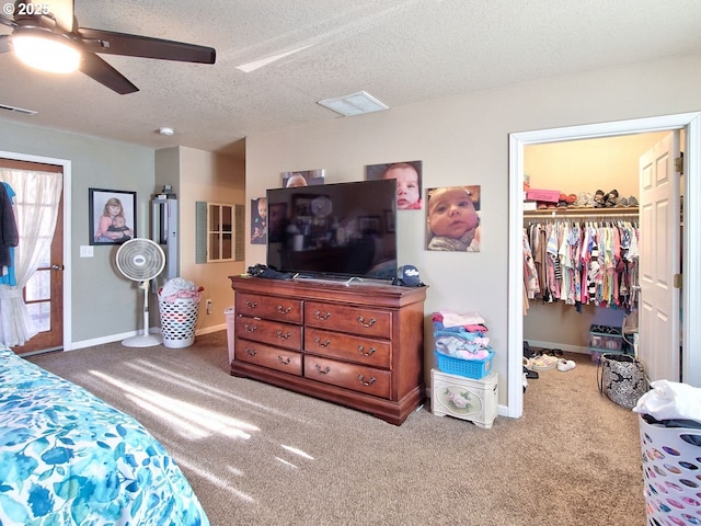 carpeted bedroom with ceiling fan, a spacious closet, and a textured ceiling