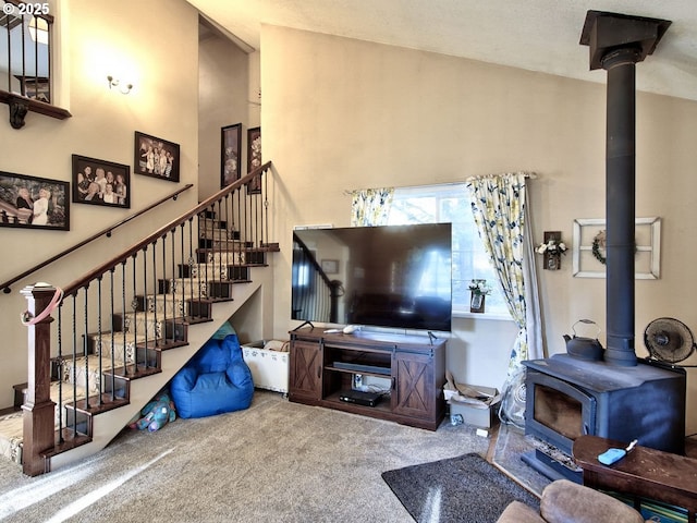 living room with carpet flooring, a towering ceiling, and a wood stove