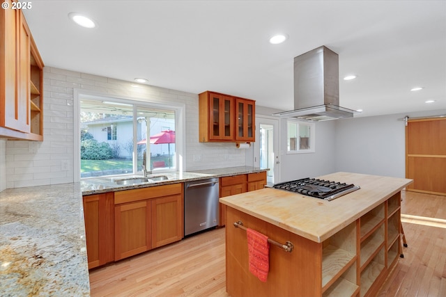 kitchen with a kitchen island, island exhaust hood, light stone counters, light hardwood / wood-style floors, and stainless steel appliances