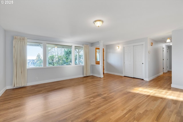 empty room featuring decorative columns and light hardwood / wood-style flooring