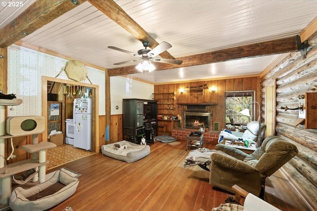 2128 Starveout Creek Rd, Azalea, OR 97410 - living area featuring beam ceiling, hardwood / wood-style floors, wood walls, a brick fireplace, and a ceiling fan
