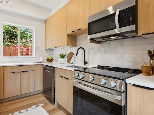 kitchen with stainless steel appliances, a sink, and light brown cabinetry