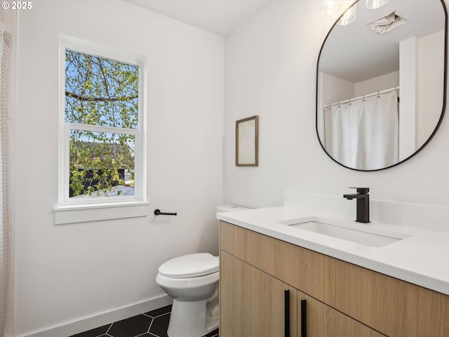 bathroom featuring toilet, vanity, tile patterned flooring, and baseboards