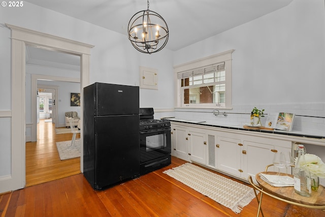 2083 NW Johnson St Unit 44, Portland, OR 97209 - kitchen featuring black appliances, white cabinetry, a chandelier, dark wood-style floors, and a sink