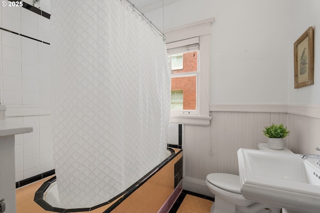 2083 NW Johnson St Unit 44, Portland, OR 97209 - bathroom featuring toilet, wainscoting, shower / bathtub combination with curtain, tile patterned floors, and a sink