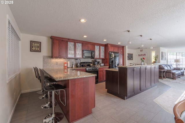 3584 NE Brogden St, Hillsboro, OR 97124 - kitchen with black appliances, a textured ceiling, a kitchen breakfast bar, decorative backsplash, and glass insert cabinets