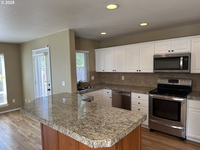 22000 SW Grahams Ferry Rd Unit C, Tualatin, OR 97062 - kitchen featuring stainless steel appliances, a sink, wood finished floors, decorative backsplash, and a textured ceiling