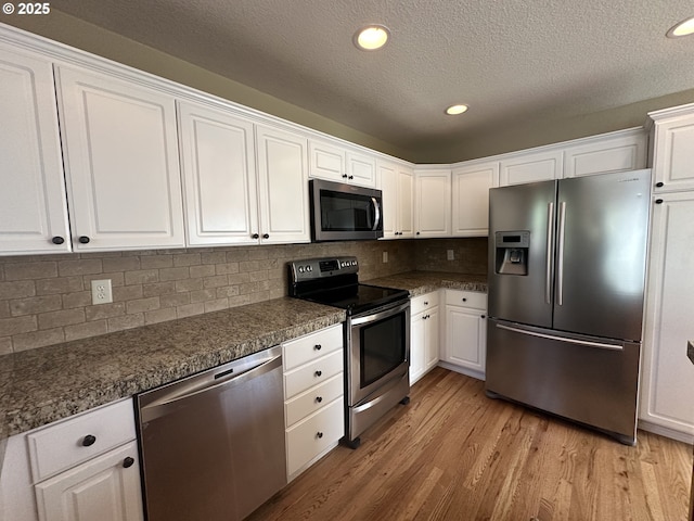 22000 SW Grahams Ferry Rd Unit C, Tualatin, OR 97062 - kitchen featuring appliances with stainless steel finishes, white cabinets, light wood finished floors, dark countertops, and a textured ceiling