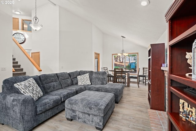 living area featuring a chandelier, light wood-style floors, stairs, and high vaulted ceiling