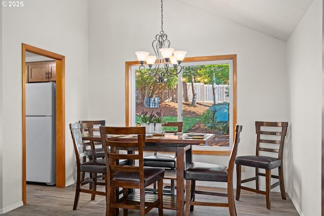 dining area with wood finished floors, a chandelier, vaulted ceiling, and baseboards