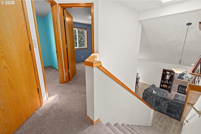 stairway featuring a brick fireplace and carpet floors