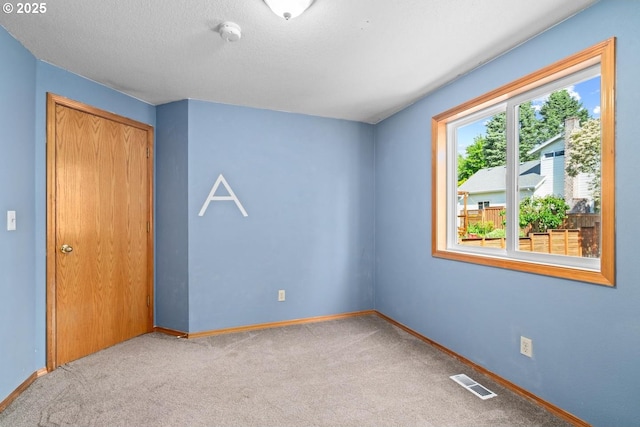 carpeted empty room featuring baseboards and a smoke detector