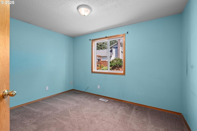 empty room with carpet flooring, a textured ceiling, and baseboards