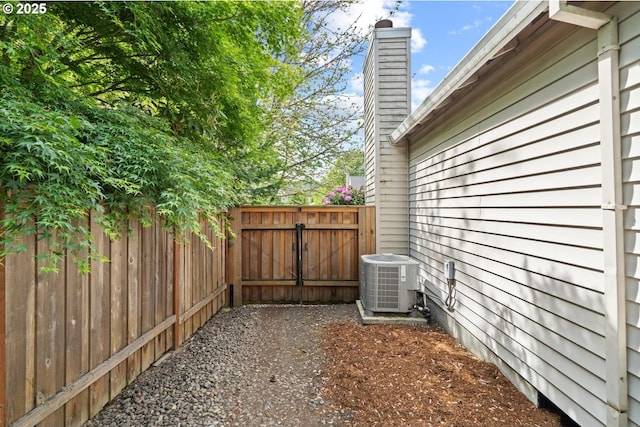 view of home's exterior featuring central AC unit, a chimney, a gate, and fence